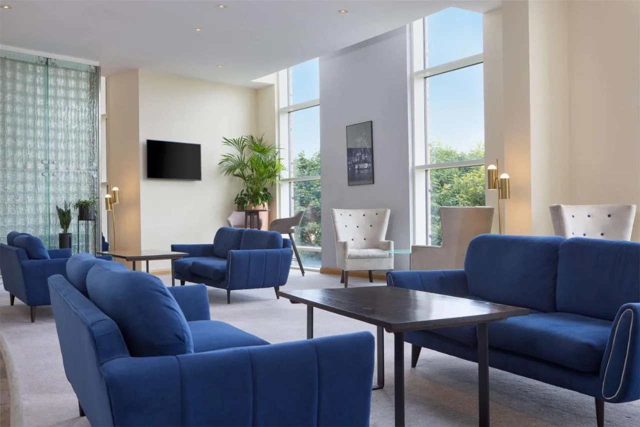 a waiting room with blue chairs and tables and windows at Hilton Newcastle Tyne Bridge in Newcastle upon Tyne
